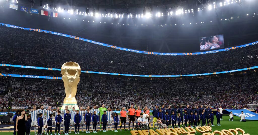 Jugadores de una selección nacional reunidos en el círculo central durante la interpretación de los himnos en el Mundial